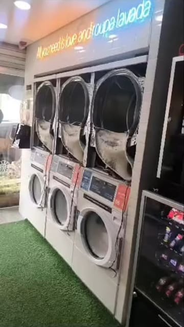 Três secadoras de uma lavanderia self-service abertas para limpeza dos tambores
